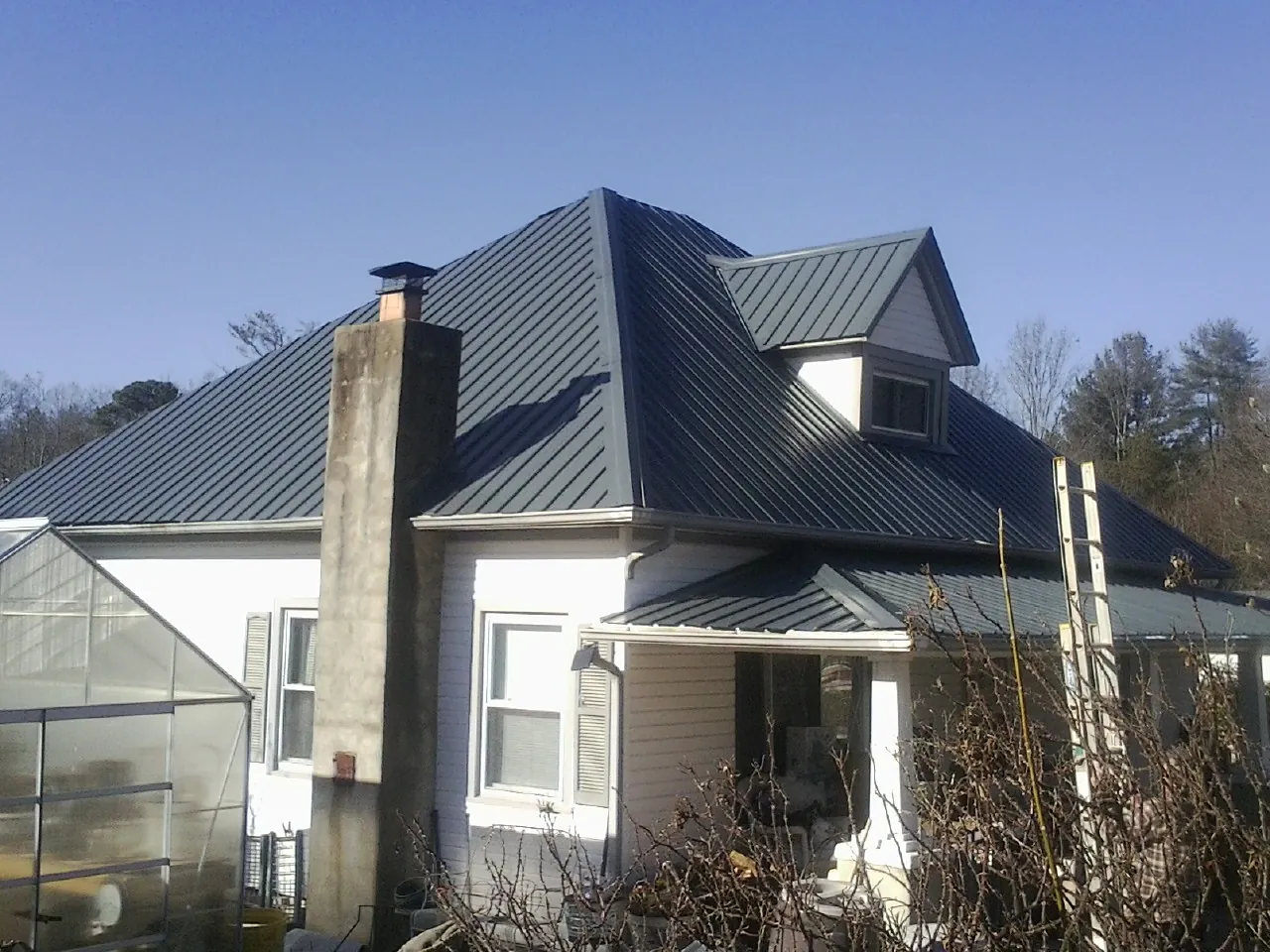 Dark blue standing seam metal roof on a white farmhouse with dormer — Slate & Tile Roof Repair by Roofing Brothers in Catawba